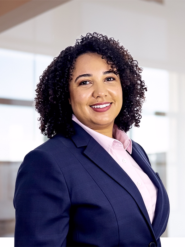 Confident African American businesswoman in navy blazer and pink shirt, smiling for corporate headshot or professional branding.