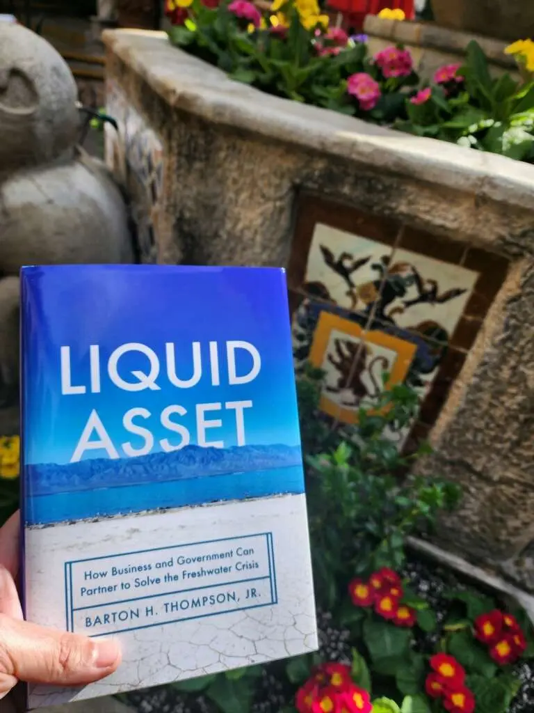 A serene landscape with a large body of water, possibly a lake or ocean, stretching out to meet a clear blue sky in the distance. The atmosphere is one of calmness and tranquility, with no people or activities visible in the scene.