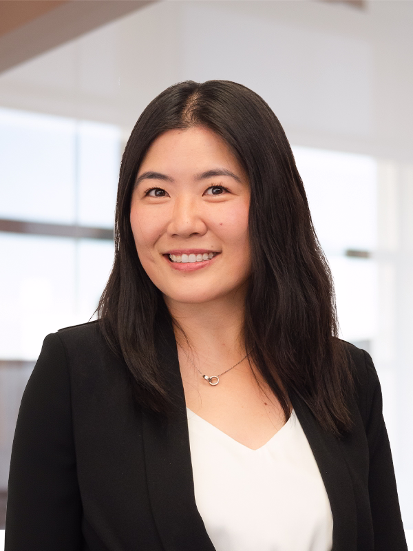 Professional headshot of a smiling Asian woman in a black blazer and white top.