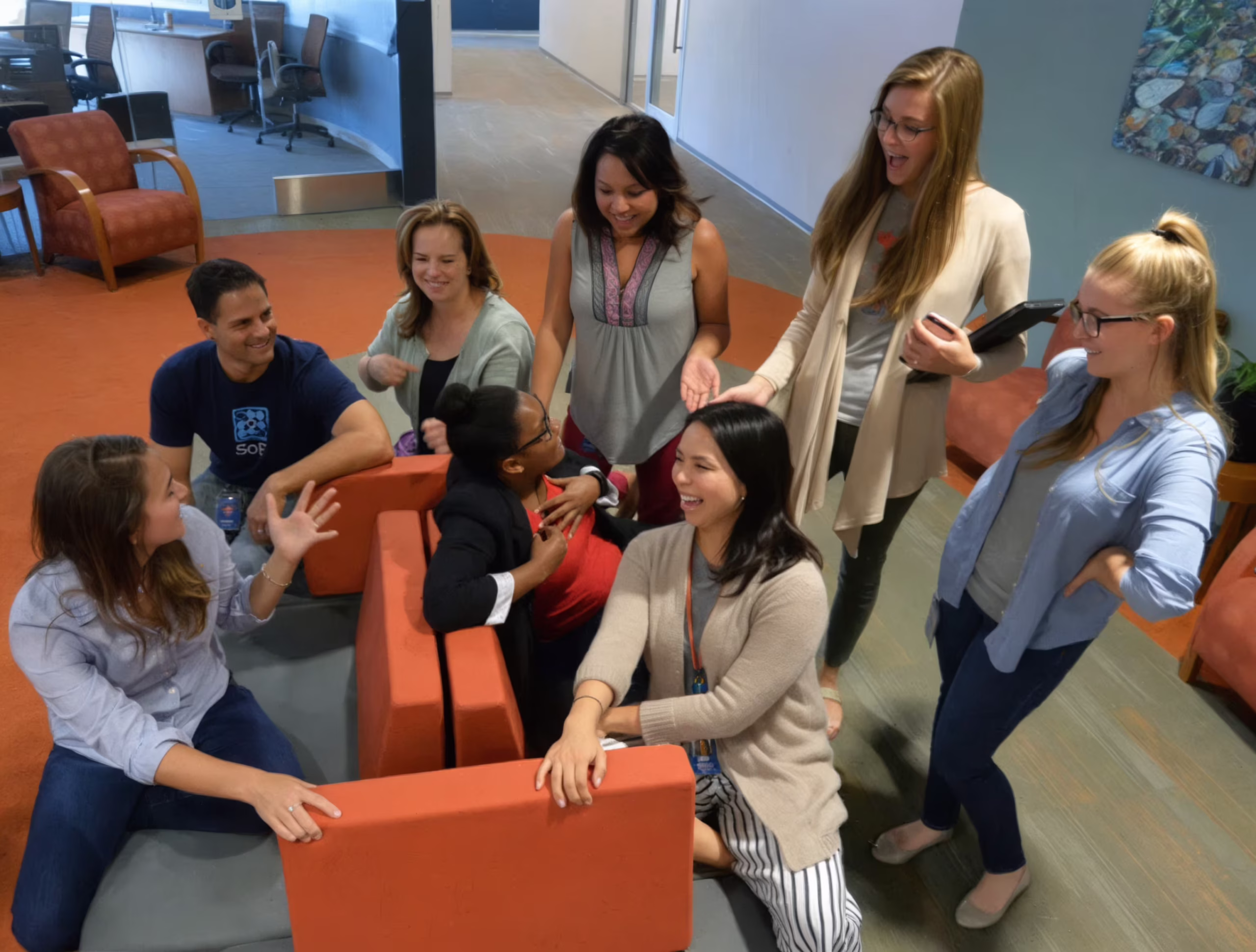 Diverse team collaborating in modern office lounge with orange modular seating